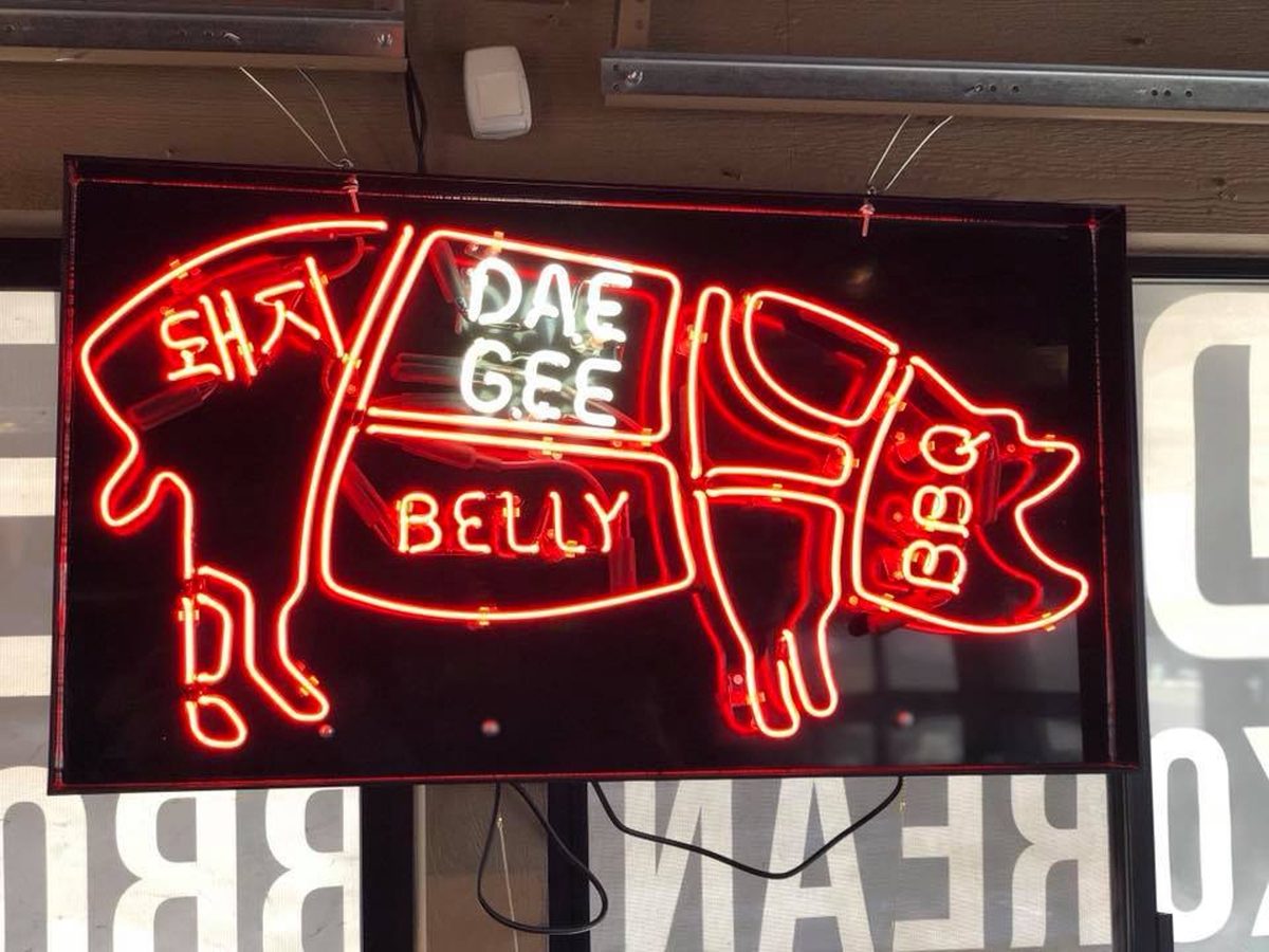 Red neon pig outline sign with Korean lettering reading Dae Gee, Belly and BBQ
